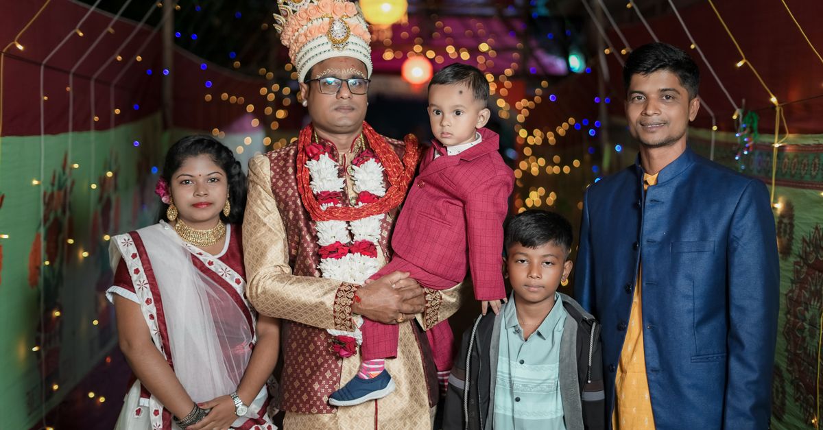 A Bengali family posing at a traditional wedding celebration with festive attire and decorations.
